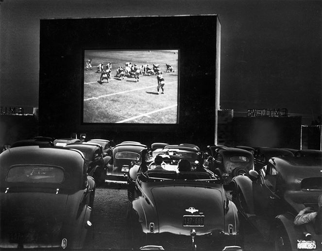 Cars parked at a drive in theater with a 53 foot wide screen.