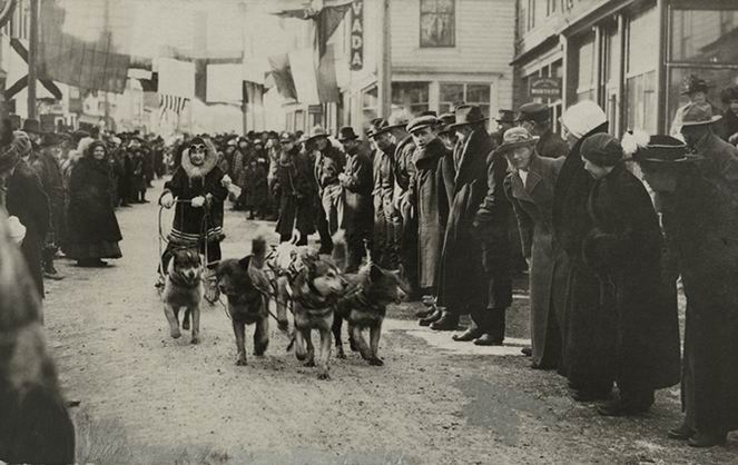 A female musher participates in a dog sled race through town.
