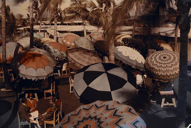 Club members on the ocean front are shaded by decorative parasols.
