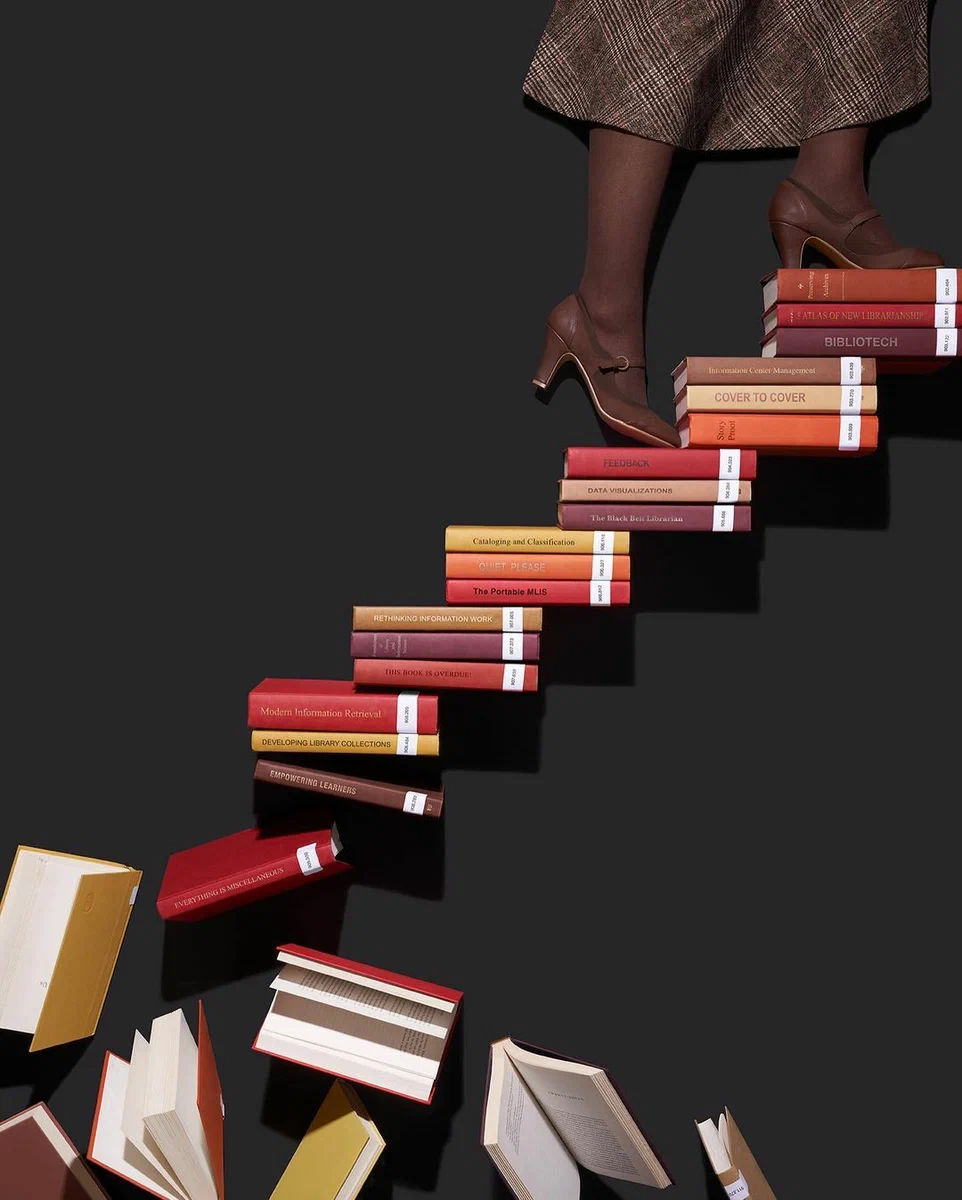 Ноги в туфлях поднимаются по лестнице из книг