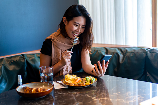 Beautiful asian woman making a video call during a meal.