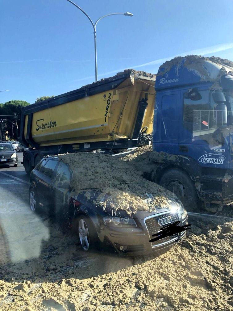 Жёлтый самосвал высыпал землю на чёрный автомобиль Audi