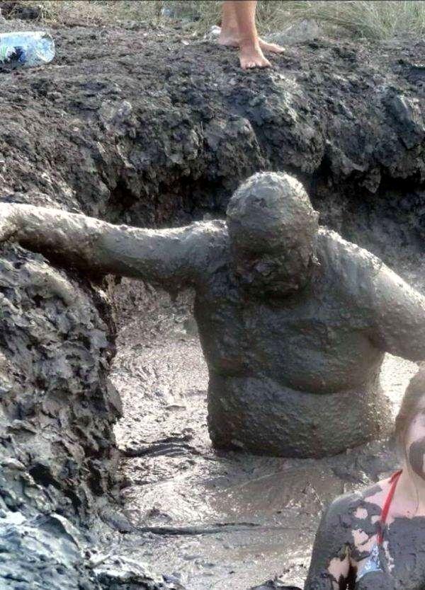 Человек с головы до ног в грязи сидит в яме