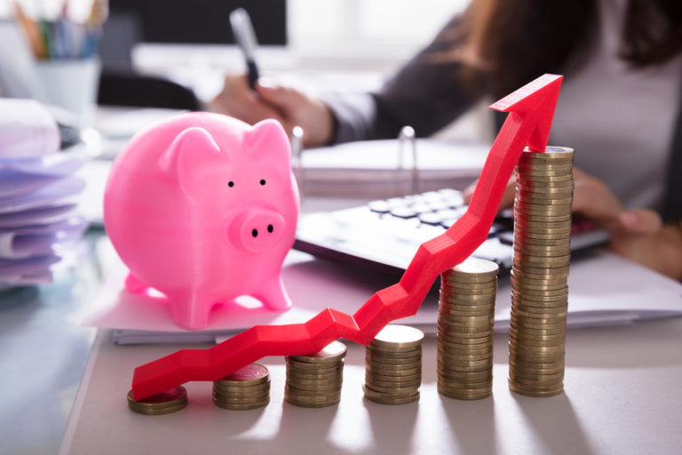 Stacked coins and arrow in front of piggybank