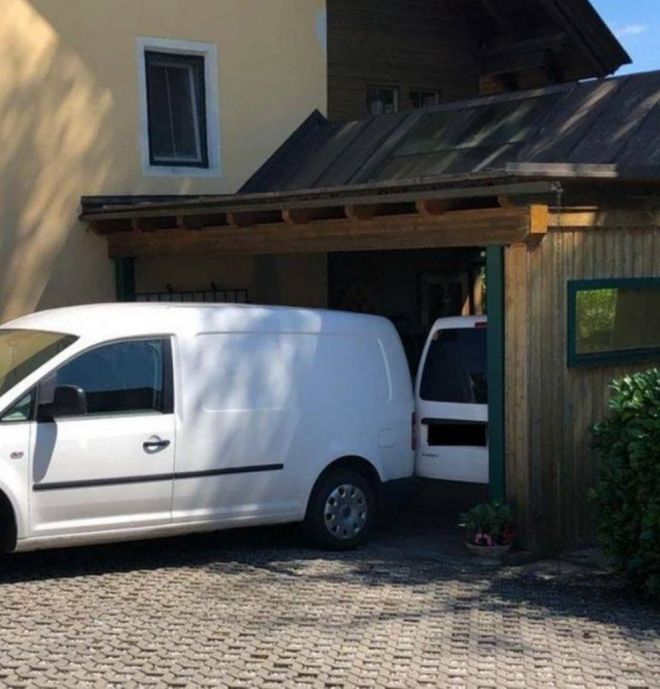 Белый фургон припаркован у деревянного сарая с открытой задней дверью