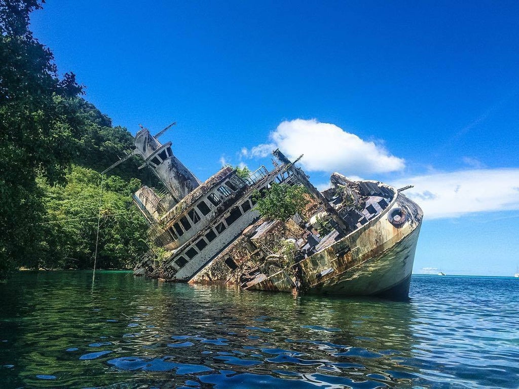 Заброшенный лайнер MS World Discoverer и природа Соломоновых островов": Фото корабля, окруженного тропической растительностью и бирюзовой водой.