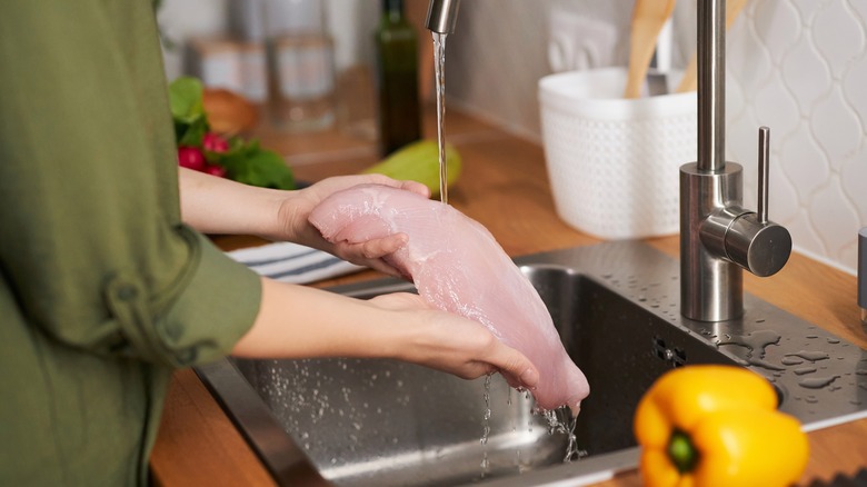 Closeup,of,young,woman,washing,chicken,breast,meat,in,tap