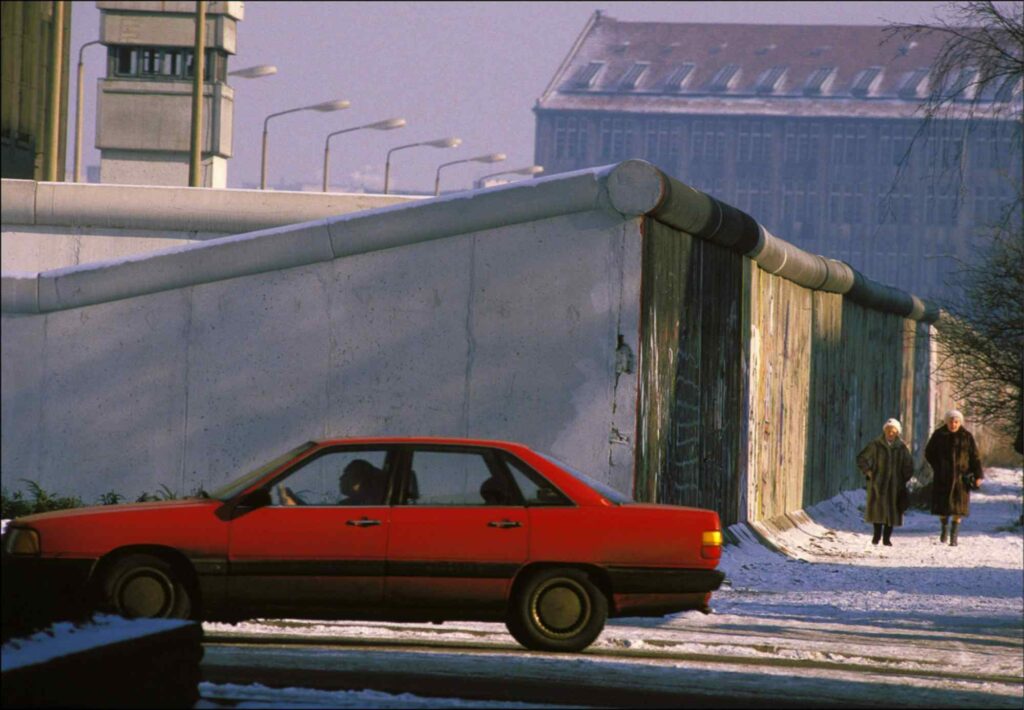 Заснеженный пейзаж и красная машина на фоне берлинской стены 1980-е годы