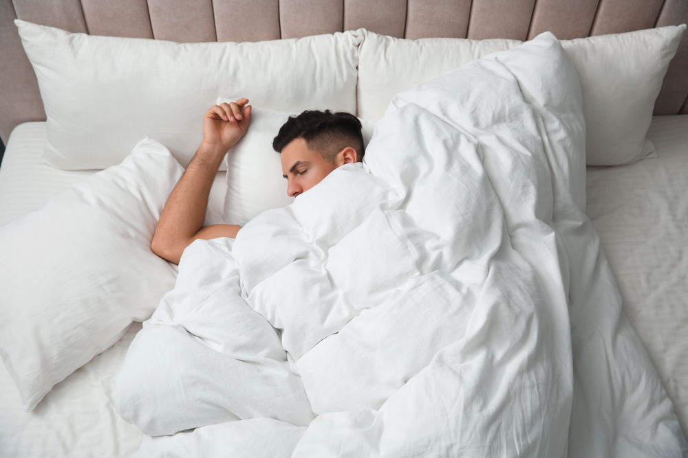 Handsome,man,sleeping,under,soft,blanket,in,bed,at,home,