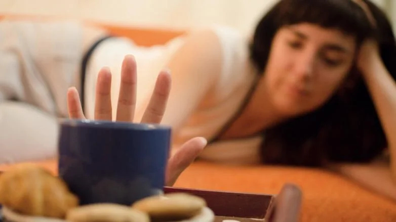 Девушка отодвигает чашку с кофе