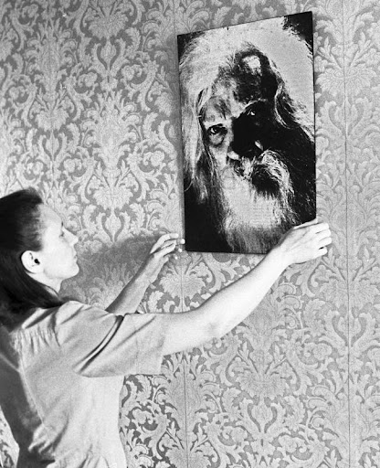 Женщина вешает портрет Порфирия Иванова на стену, последователи учения