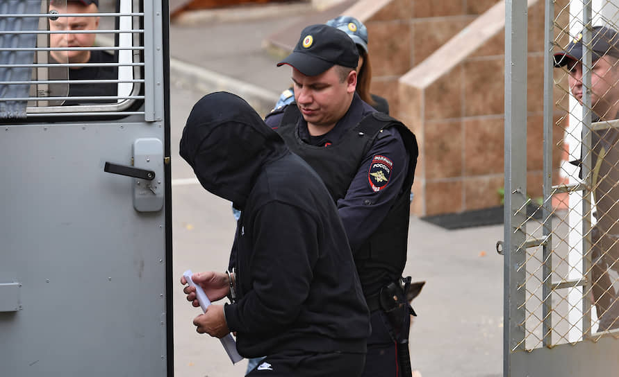 полицейские ведут человека в черном худи