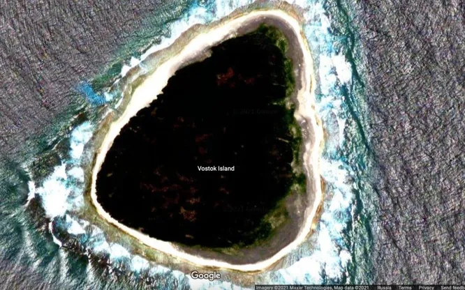 Вид с воздуха на остров Восток — тёмный лес пизонии на фоне голубого океана