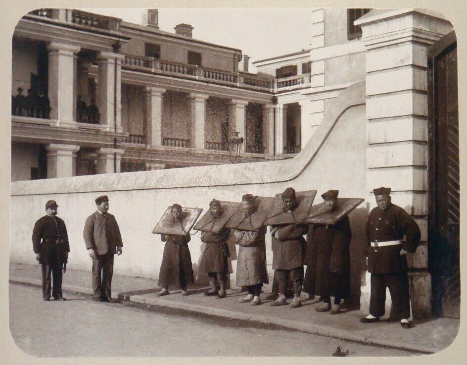 Чиновник в церемониальной одежде осматривает группу осуждённых в деревянных колодках, Китай, XIX век.