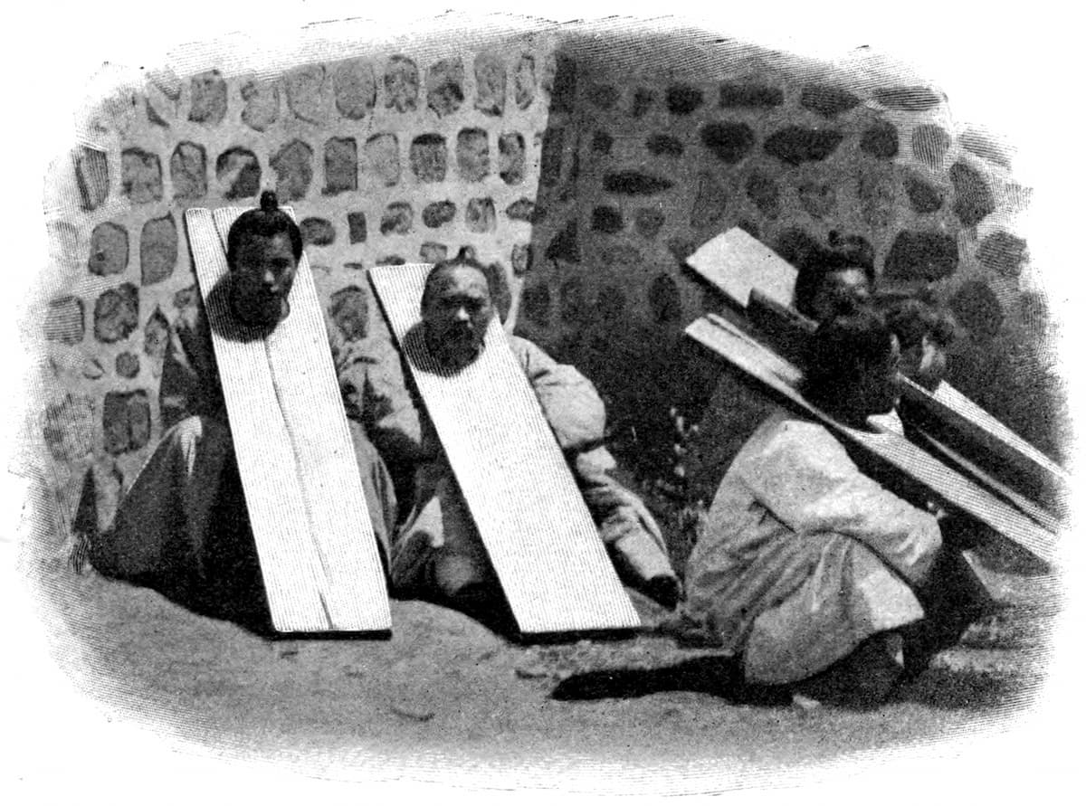 Корейский крестьянин в длинной деревянной колодке, которую он вынужден держать руками, 1904 год.