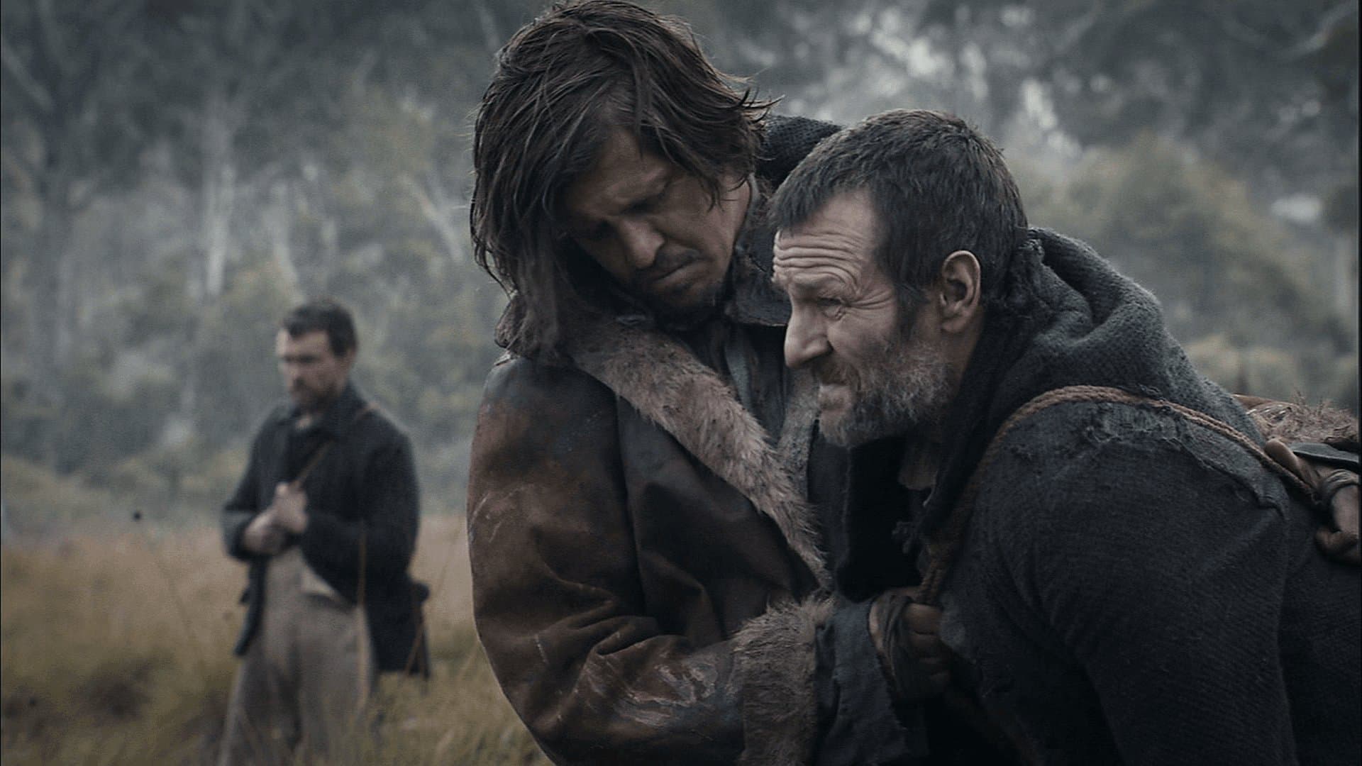 Пятеро изможденных мужчин в лохмотьях сидят на поваленном дереве посреди непроходимого леса