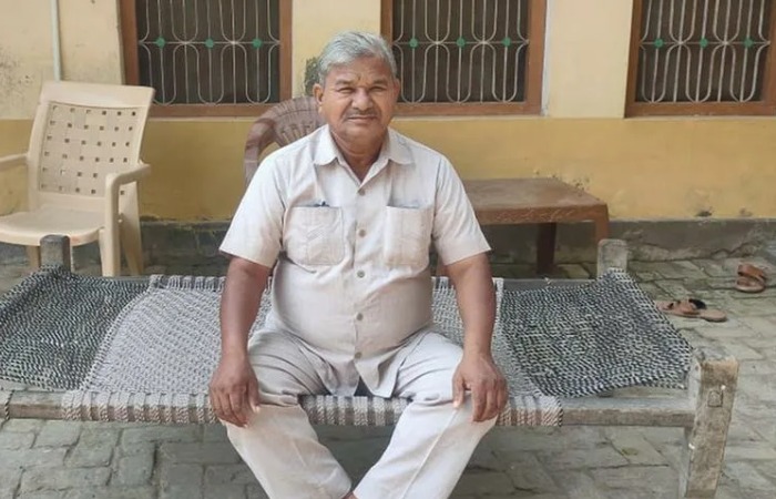 Лал Бихари Мритак говорит по телефону, сидя за столом с документами