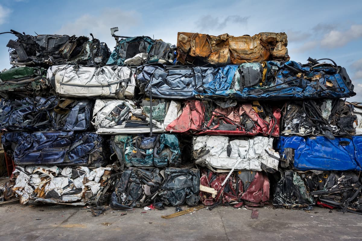 Спрессованные в кубы автомобили на свалке металлолома, готовые к отправке на переплавку.