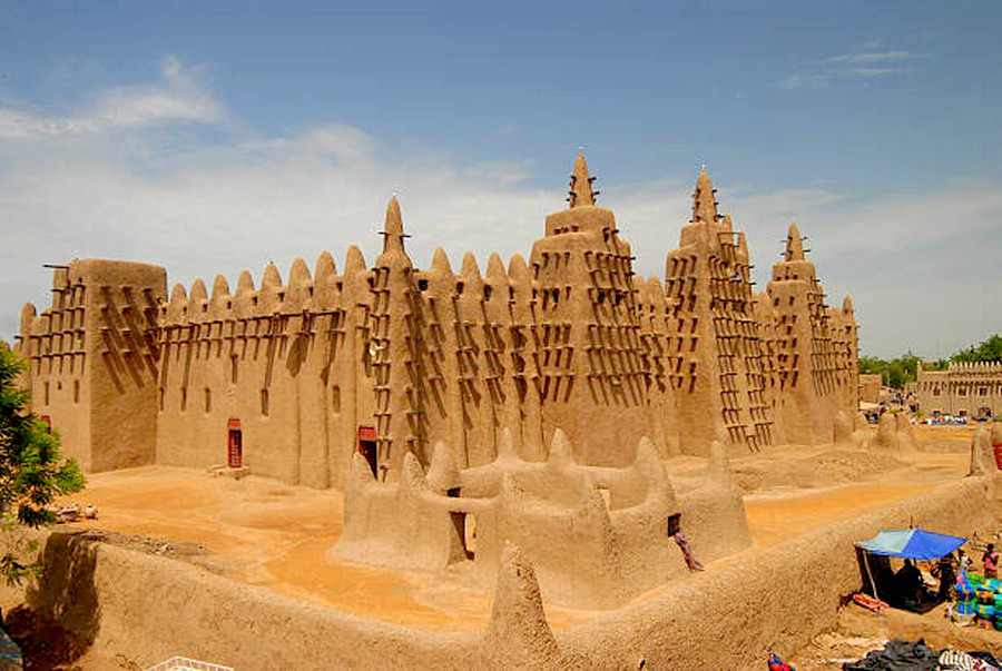 Вид на глиняные дома и мечеть в Дженне с людьми на улице, типичная африканская архитектура