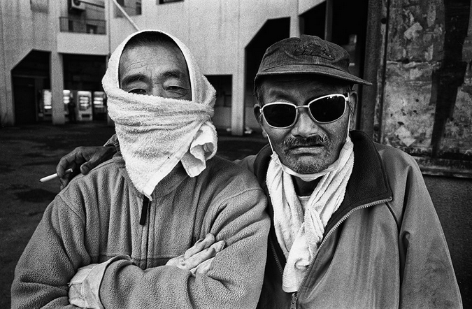 Двое бездомных мужчин на улице у стены