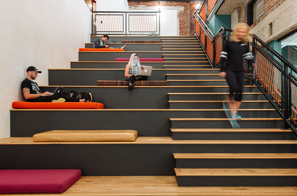 Кадр из коворкинга WeWork с людьми, работающими на лестнице-амфитеатре