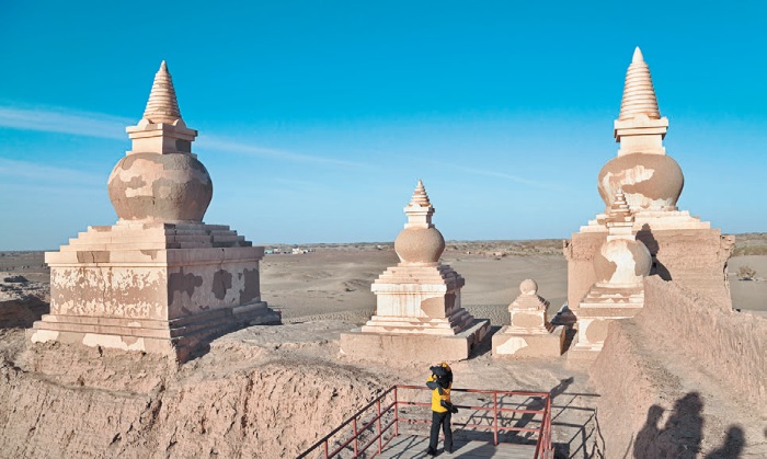 Турист у буддийских ступ масштаб руин Хара-Хото в пустыне