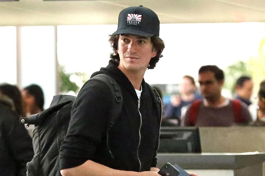 Портрет Адама Неймана (Adam Neumann) в кепке и с рюкзаком в аэропорту