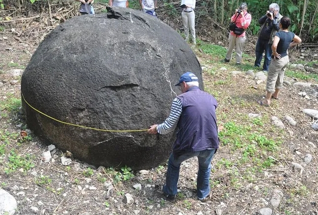 Мужчина замеряет каменную сферу, другие люди фотографируют &mdash; исследование сфер Дикис
