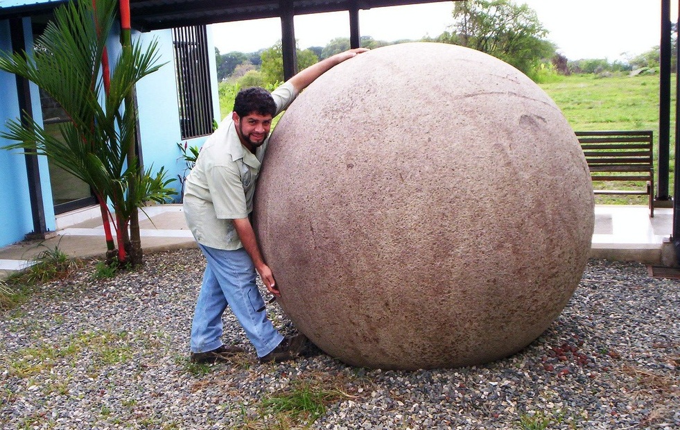 Турист обнимает огромную каменную сферу культуры Дикис в Коста-Рике