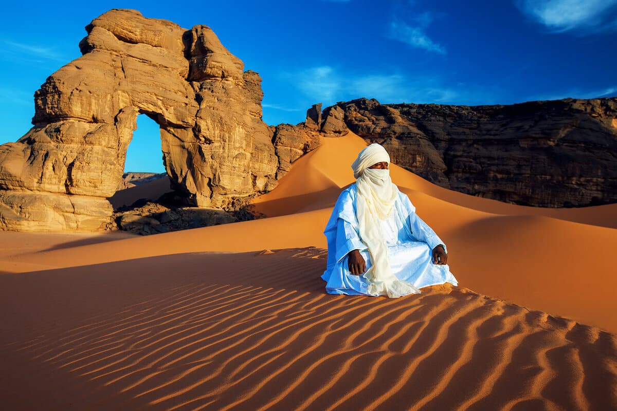 Туарег в традиционной одежде в пустыне Сахара у скал Тассилин-Аджер