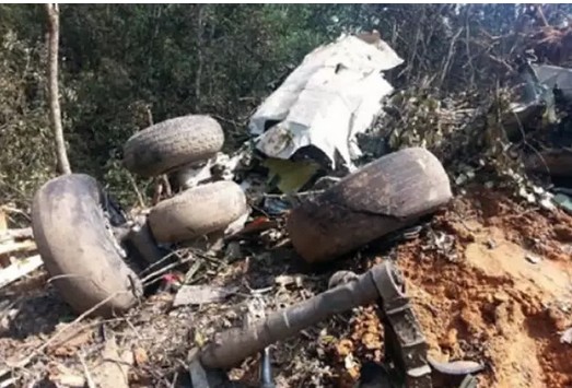 Разбросанные по склону холма обломки самолёта и личные вещи пассажиров на фоне гор