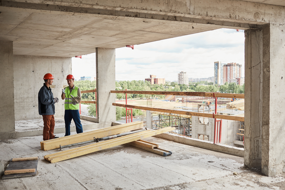 Wide,angle,view,at,two,construction,workers,wearing,hardhats,while
