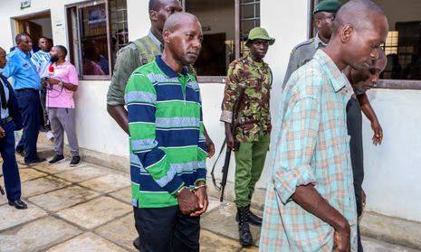 Полицейские ведут в наручниках арестованного пастора Пола Макензи