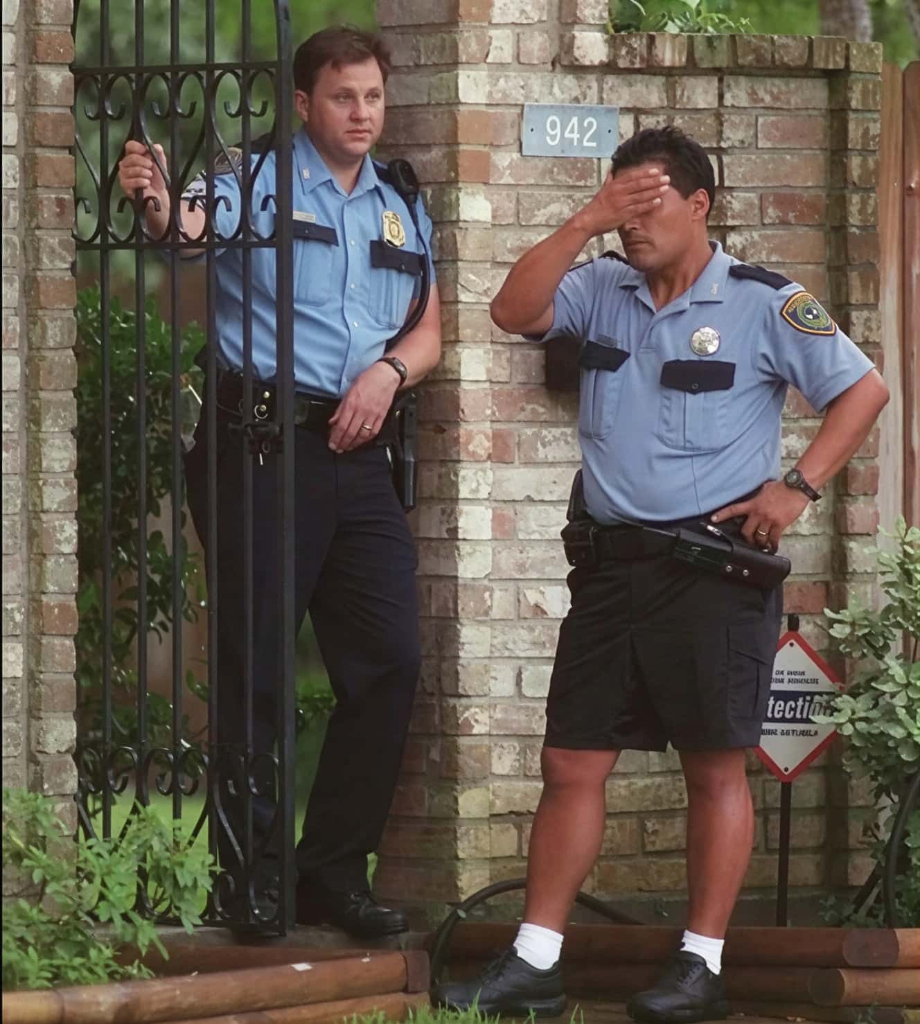 Полицейские офицеры у железных ворот дома №942 Йейтс (Yates) в день убийства, один держится за голову в отчаянии