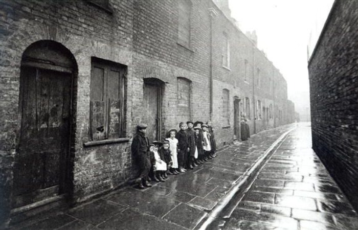 Дети на улице в Англии рядом с домами, где часть окон заложена кирпичом