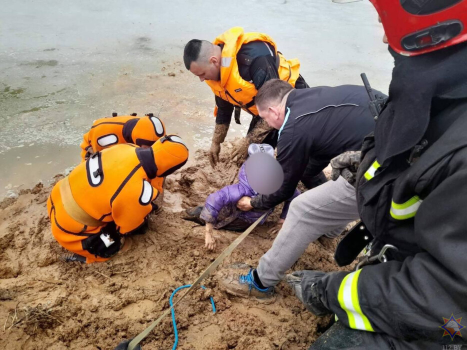 Спасательная операция: спасатели в оранжевых костюмах вытаскивают человека из зыбучих песков на берегу