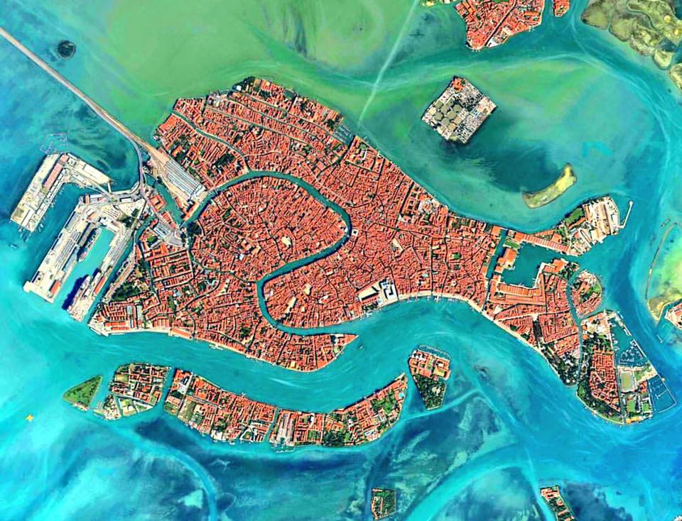 Аэрофотосъёмка островной застройки Венеции: черепичные крыши плотно прилегают друг к другу, а каналы разрезают город на отдельные фрагменты