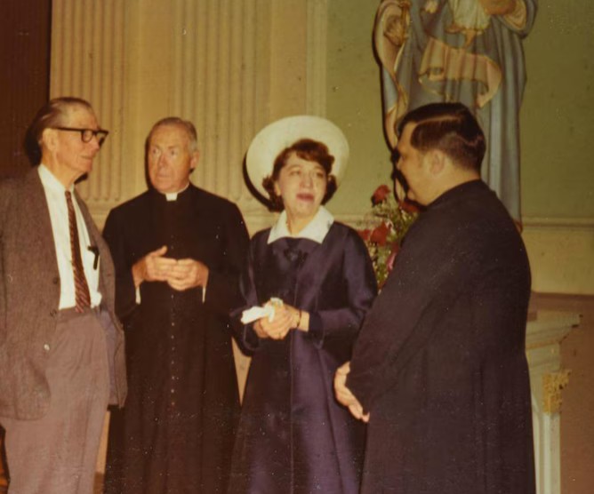 Джин Диксон в чёрном платье в окружении католических священников