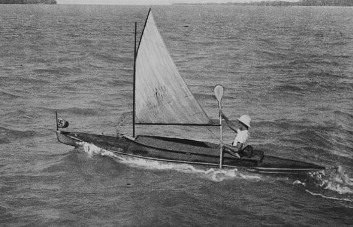 Оскар Спек плывёт под парусом на байдарке со свастикой на носу