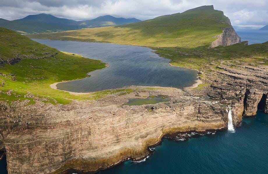 Панорамный вид на озеро Сёрвогсватн и водопад стекающий в океан Фареры