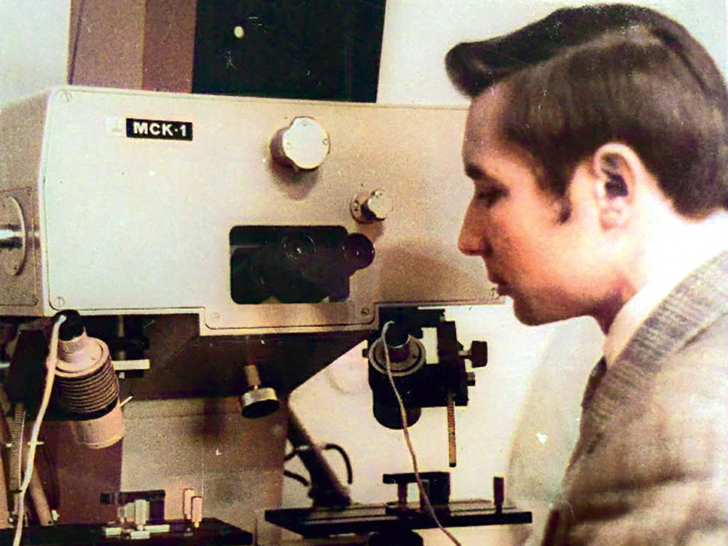 Молодой оперативник у микроскопа в отделе ЭКЦ