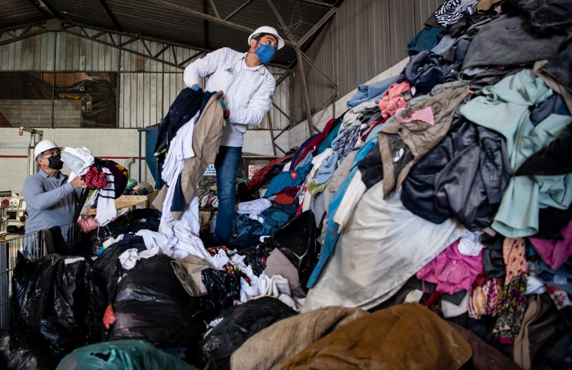 Мужчины разгружают тюки с подержанной одеждой из грузовика в порту Икике