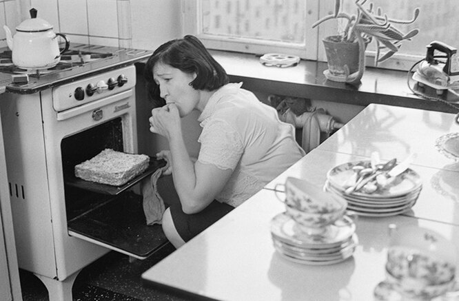 Женщина достает торт из духовки на советской кухне