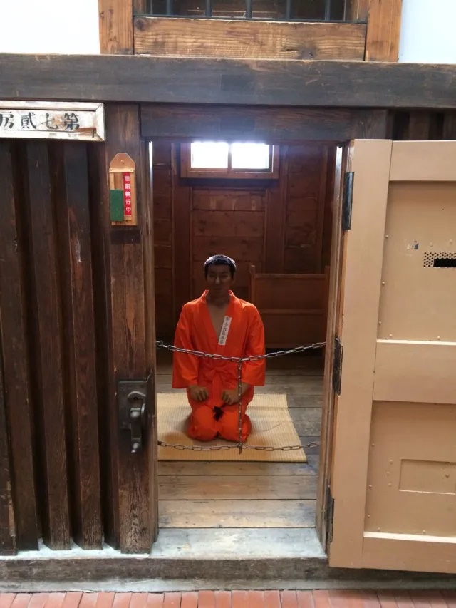 Восстановленная тюремная камера в музее Абасири: деревянные нары, решётка, минимальная обстановка