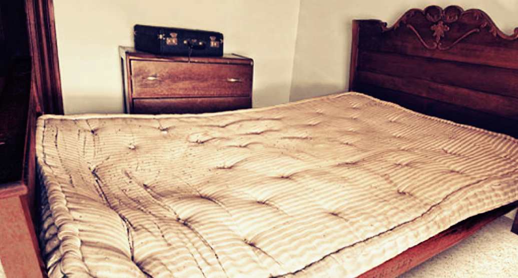 Фотография старого продавленного матраса на кровати