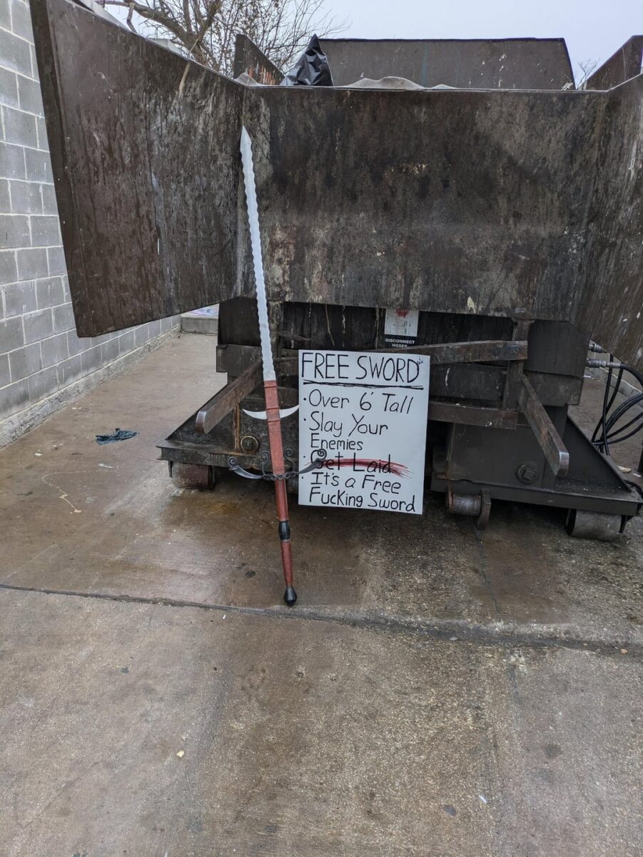 Возле мусоровоза стоит огромный меч. Рядом надпись на английском - Бесплатный меч