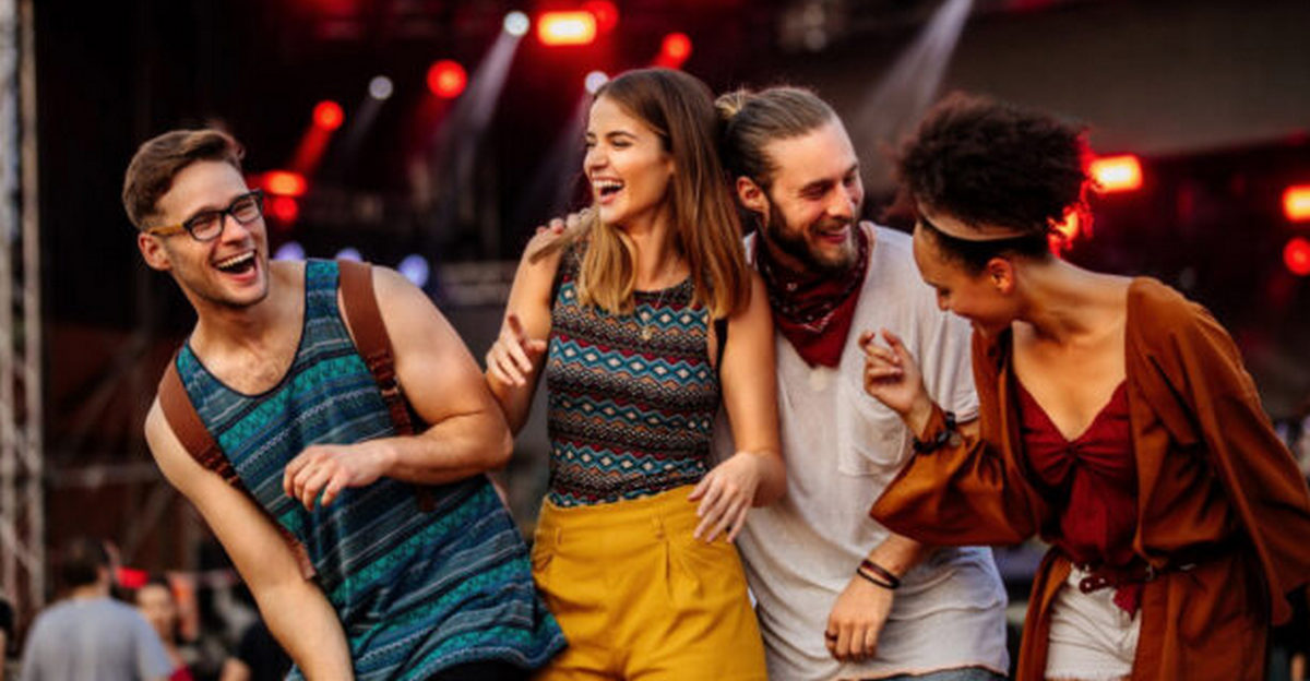 Группа молодых миллениалов весело танцует и смеется на фестивале