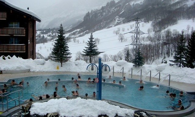 Группа друзей отдыхает в бассейне у русской бани на заснеженном дворе