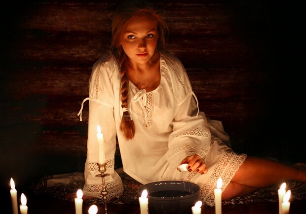 Девушка в ночной сорочке гадает во сне с миской и свечами в полумраке