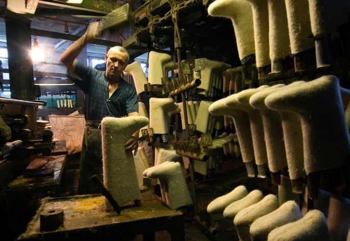 Мастер в мастерской валяет валенки вручную на специальных колодках в производственном цехе